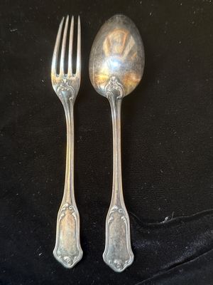 deux cuillères en argent et une fourchette posées sur une nappe noire