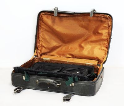 une valise noire dont le couvercle est ouvert, posée sur une surface blanche