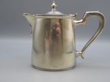 a silver tea pot with a handle on a table