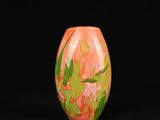 un vase orange et vert posé sur une surface noire