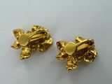 a pair of gold tone flower earrings on a white surface