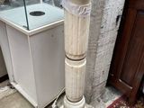 un socle blanc surmonté d'un bain d'oiseaux, placé devant une vitrine