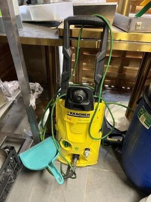 a yellow pressurer sitting on the floor next to a blue trash can
