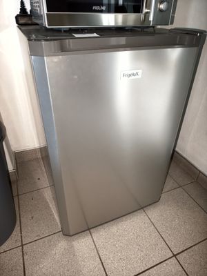 a small silver refrigerator in the corner of a kitchen