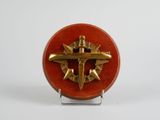 une image représentant une broche rouge et dorée ornée d'une croix