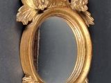 a gold mirror with a bird on it on a table