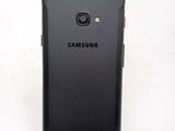 the back of a black samsung galaxy s4 phone on a white surface