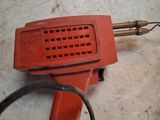 a red blow dryer sitting on the floor next to a black hose