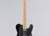 a black electric guitar hanging from a white wall