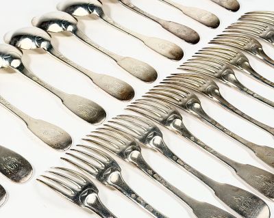 un grand nombre de cuillères et de fourchettes en argent disposées sur une table