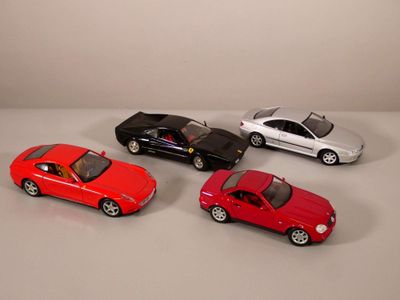 quatre petites voitures sont alignées sur une surface blanche