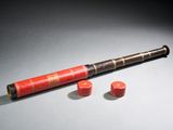 un vieux télescope avec un étui rouge et deux boutons rouges