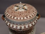 a large bowl with a lid sitting on top of a stack of plates