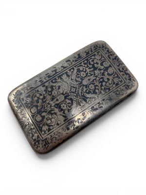 an antique silver cigarette case with a floral design on it