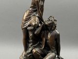 an image of a bronze statue of a woman and a man sitting on a rock