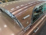 a brown car parked in a garage with other cars in the background