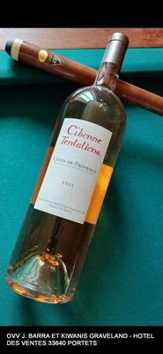 une bouteille de vin et un cigare posés sur une table de billard
