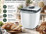 une machine à pain blanche posée sur un plan de travail, à côté du pain