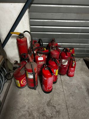 Plusieurs extincteurs sont alignés sur le sol devant une porte de garage