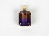 un gros plan d'un pendentif violet et jaune sur une surface blanche
