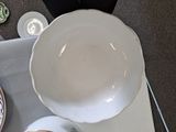 a white bowl sitting on top of a table next to a cup and saucer