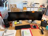 un bureau équipé de deux écrans, d'un clavier, d'un téléphone et d'autres fournitures de bureau