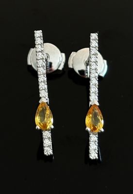 paire de boucles d'oreilles en saphir jaune et diamants sur un fond noir