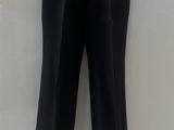 black leather pants hanging on a hanger against a white wall