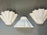 two white scallop shaped wall sconces on a gray wall