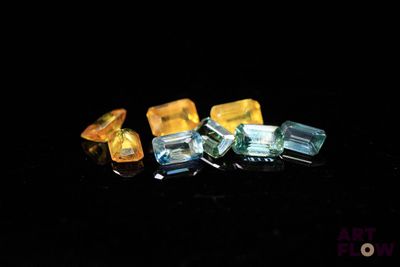 three pieces of yellow and blue glass sitting on top of a black surface