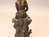 bronze statue of a woman sitting on a rock with her hands on her knees