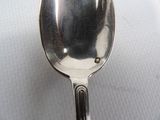 a silver spoon with a hole in it on a white surface