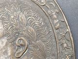 a metal plaque with a head of a man on it