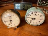 two clocks sitting on a table next to each other