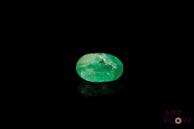a close up of a green emerald on a black surface