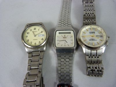 trois montres sont assises l'une à côté de l'autre sur une surface blanche