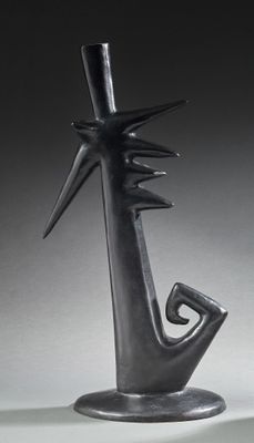 une sculpture noire représentant une personne tenant un oiseau, posée sur une table