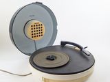 un tourne-disque posé sur une table, à côté d'une tasse