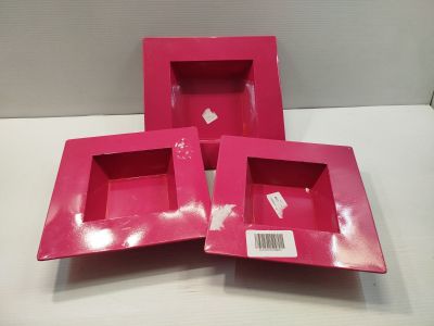 trois boîtes roses sont posées sur une surface blanche, avec une étiquette de prix
