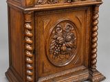 une vieille armoire en bois ornée de sculptures sur la façade et les côtés