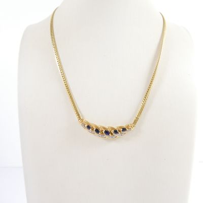 a gold necklace with blue stones on a mannequin neck