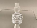une figurine en verre représentant un oiseau perché sur une table en verre