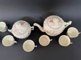 many cups and a teapot sitting on a table
