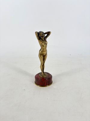 une petite statue en bronze représentant une femme, posée sur un socle en marbre