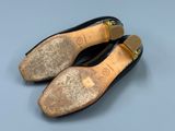 pair of black leather shoes with gold buckles on a blue surface