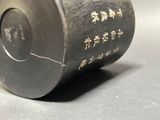 a black vase with writing on it sitting on a table