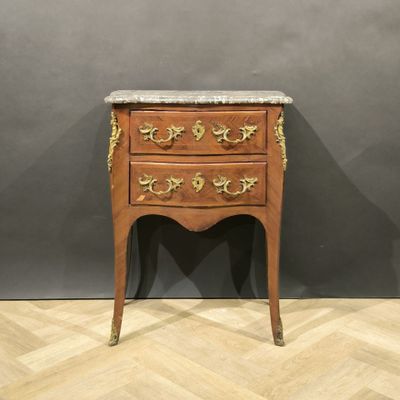 une vieille commode en bois avec un plateau en marbre, posée sur un sol à motif en chevrons