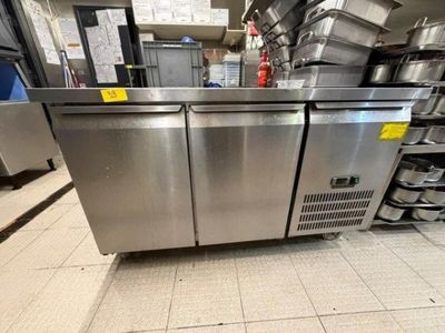 une grande cuisine en inox avec de nombreuses casseroles et poêles posées sur le plan de travail