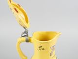 a yellow pitcher with a spoon on top of it