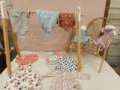 de nombreux vêtements de bébé suspendus à une corde à linge posée sur un lit